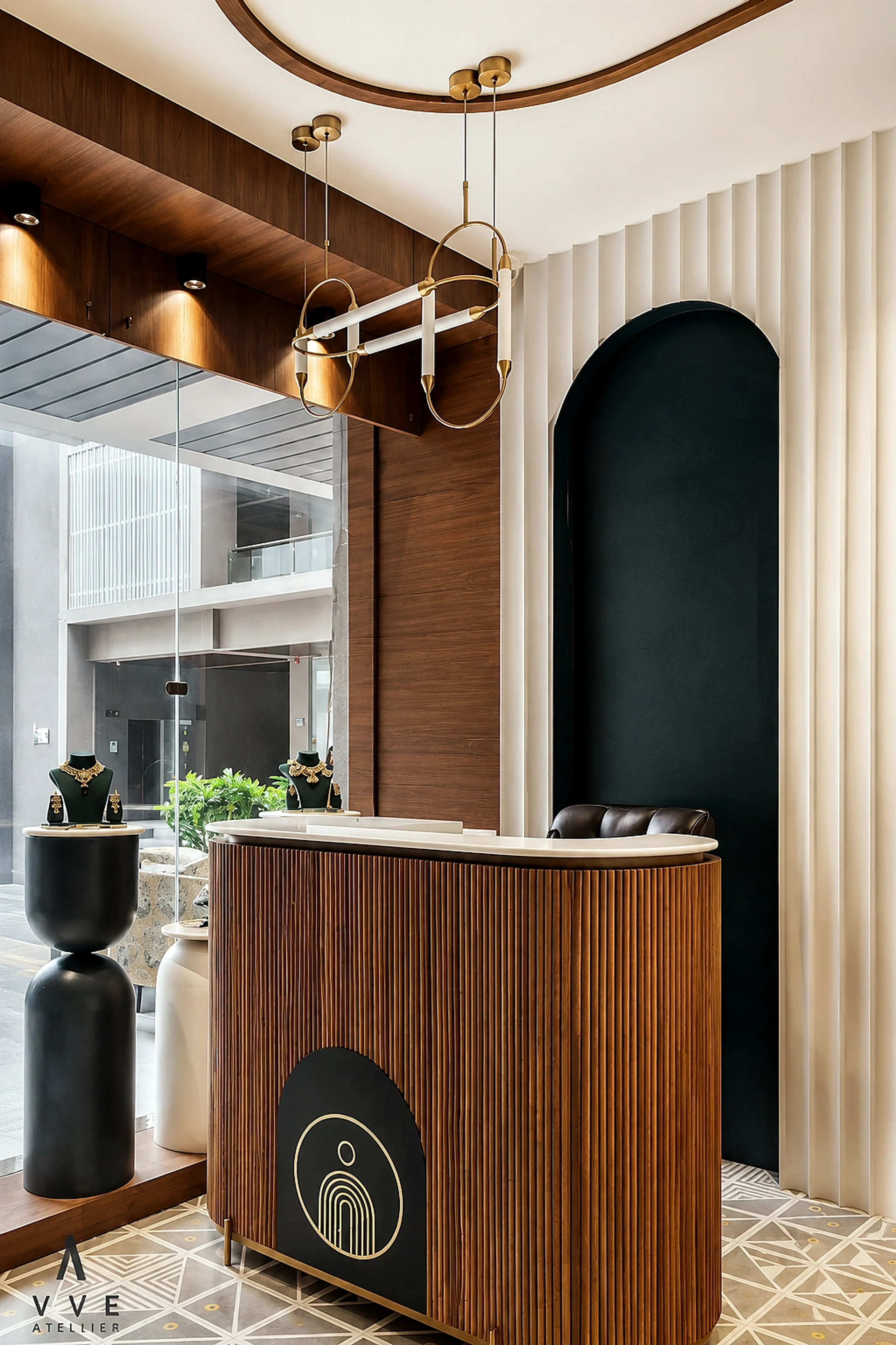 Jewellery showroom reception counter with warm wood, fluted surfaces, and sculptural pendant lights